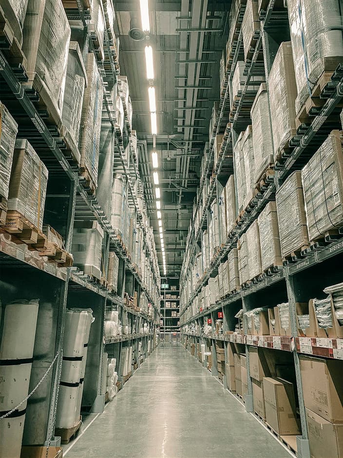 Centro de distribución moderno con pasillos organizados y estanterías repletas, mostrando la capacidad logística de ACTM Dist