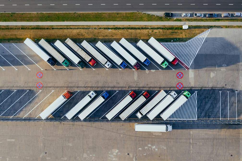 Vista aérea de camiones estacionados ordenadamente en un centro logístico, un ejemplo de la coordinación de transporte que ofrece ACTM Dist